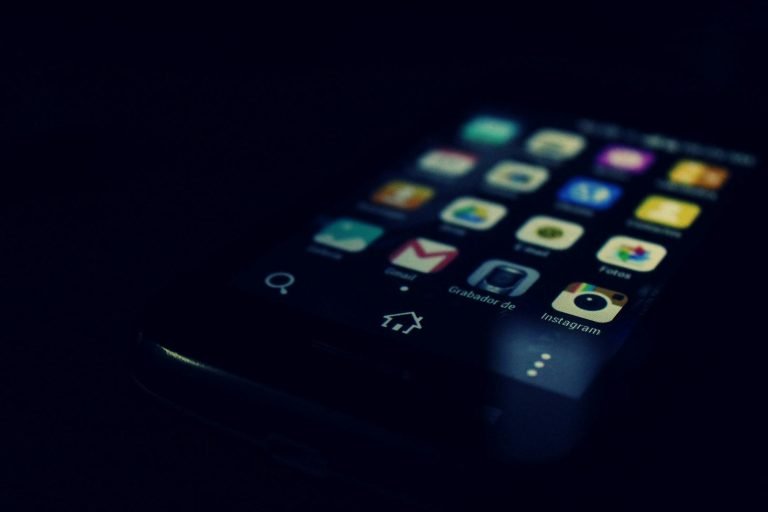 Home Dark-themed close-up of a smartphone screen highlighting various apps and touchscreen technology.